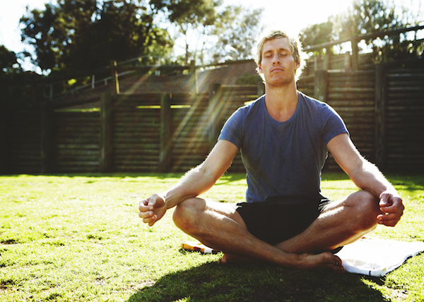 Young conscious man meditating outdoors