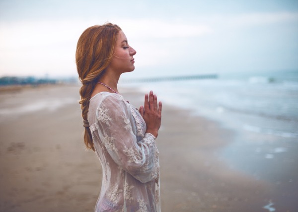 woman connecting to the sacred on the beach