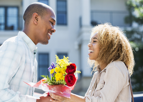 Man giving a bouquet of flowers to his partner.